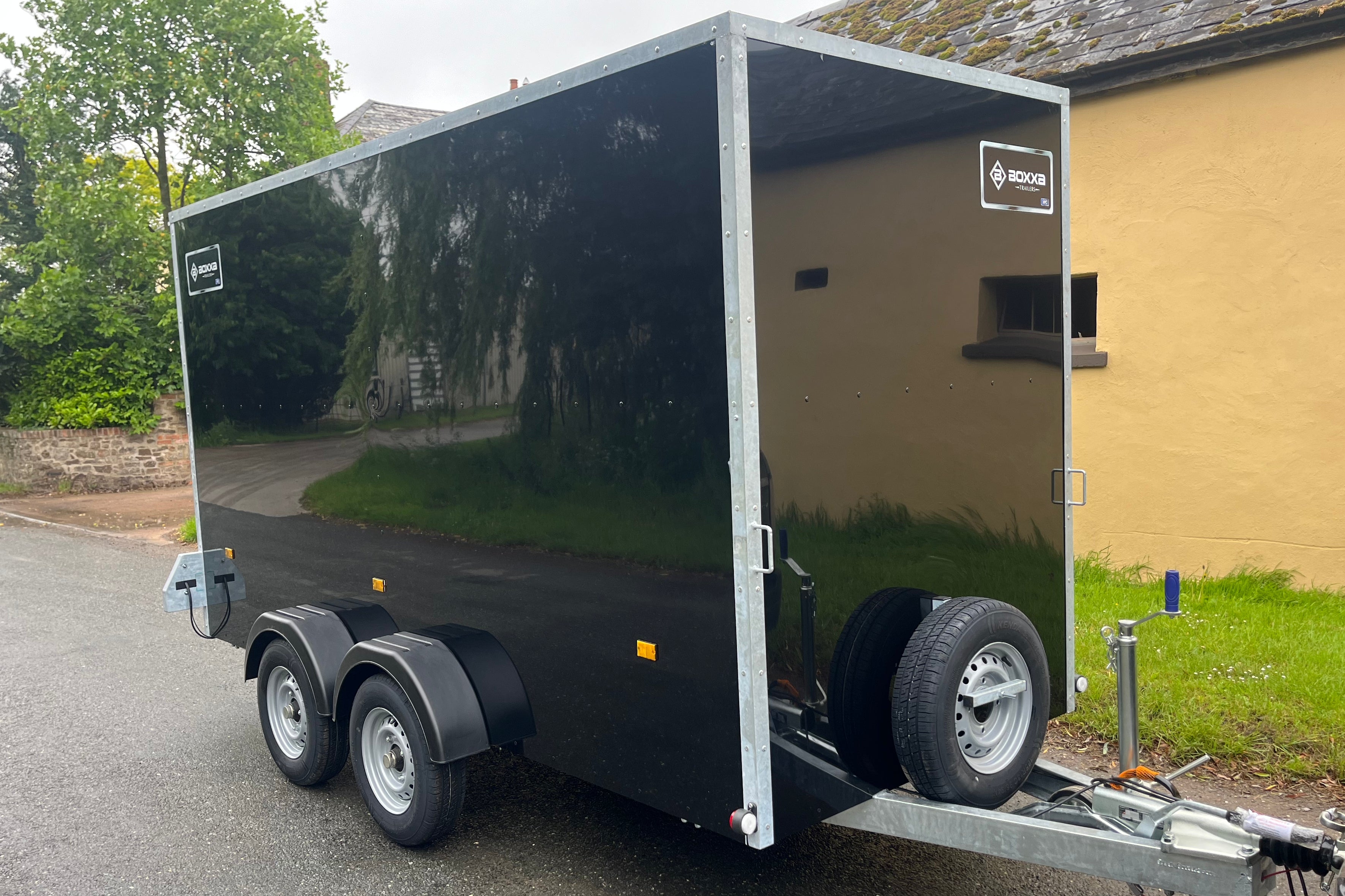 Large black boxxa trailer with twin axles and spare wheel mounted at the front of the trailer.