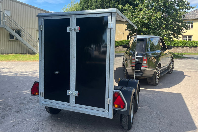 rear view of a black boxxa trailer with closed barn doors and steel surround. 