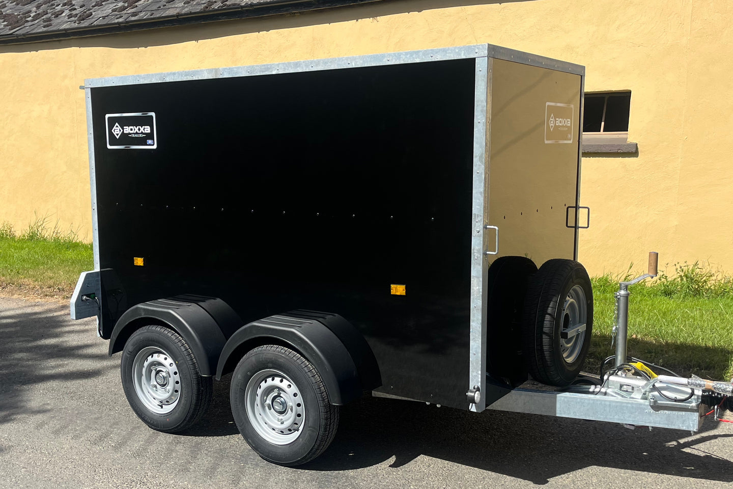 side view of a twin axle black boxxa with 2 of the 4 wheels visible.