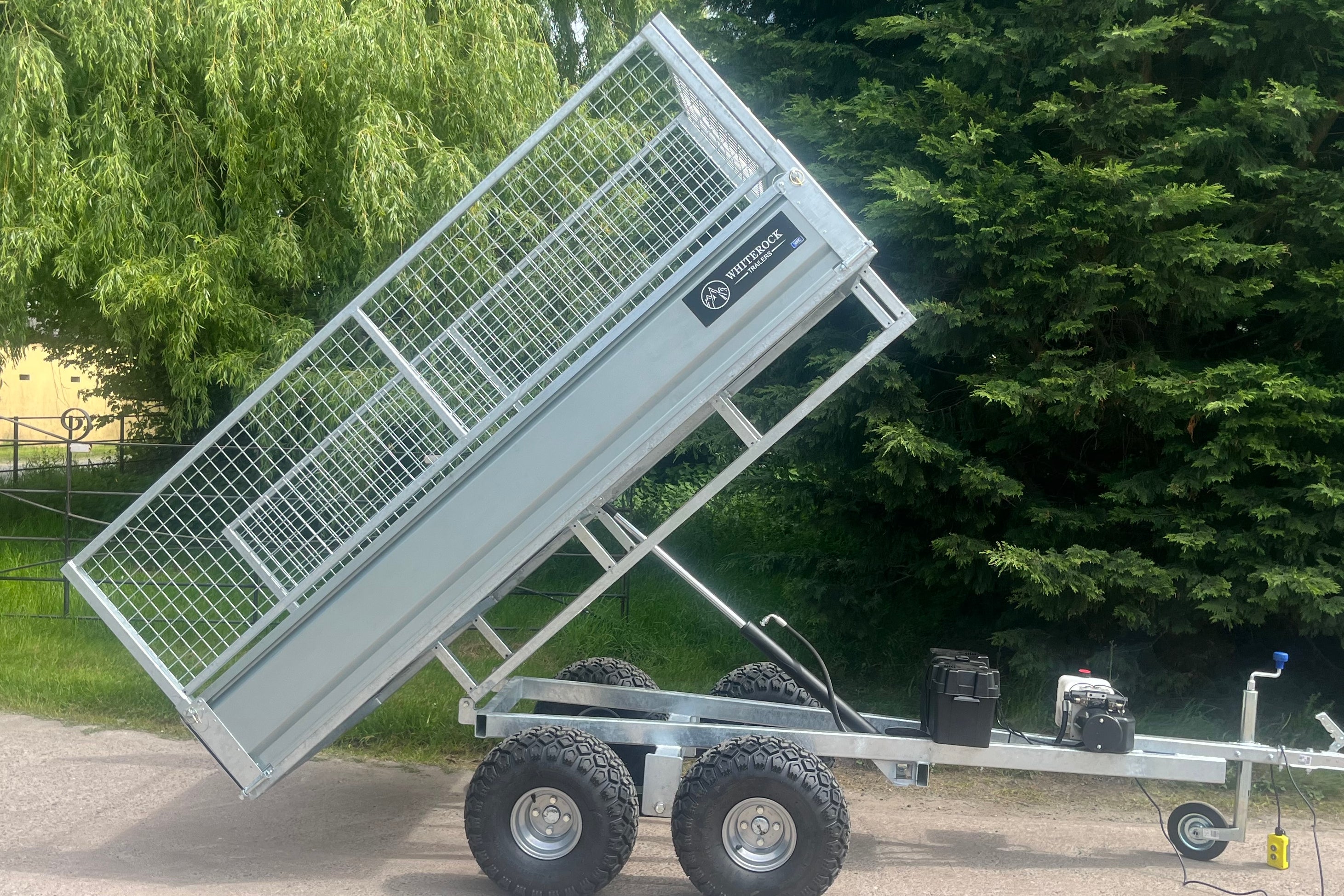 Side view of a tipping trailer with mesh sides in full tipping position.