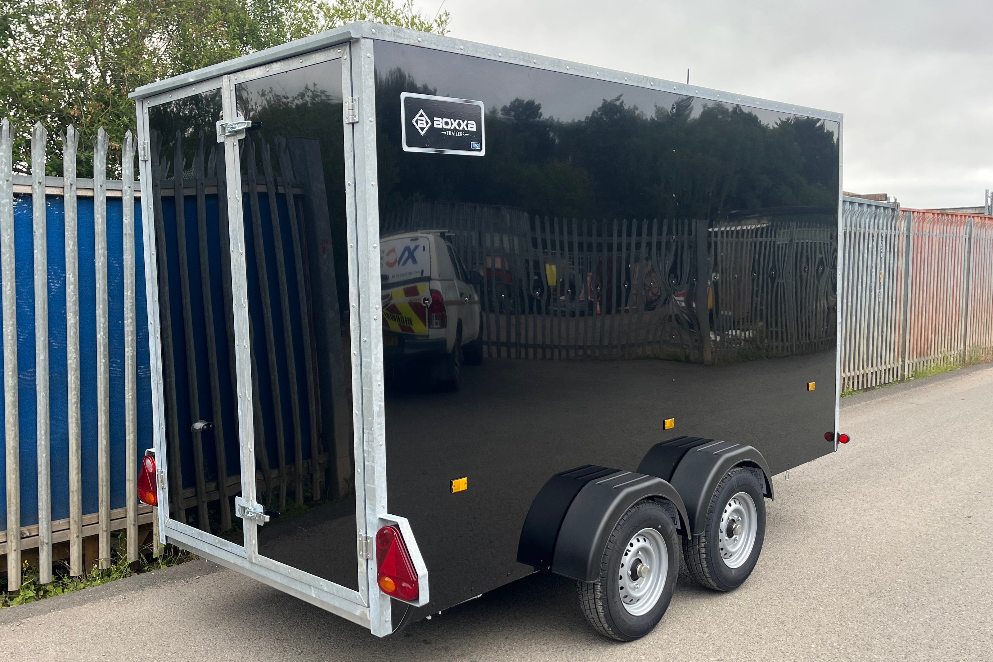 Black boxxa trailer side view with rear barn doors and twin axle.