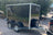 A black boxxa trailer with silver metal trim and dual rear wheels, The trailer has visible' logos on the side panels.