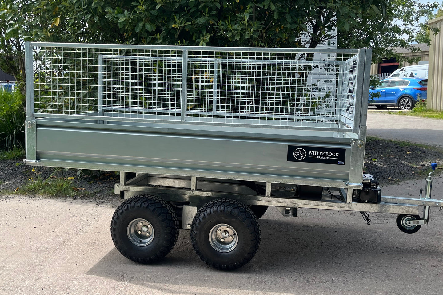 Galvanised steel trailer with mesh sides and twin axle. Jockey wheel is in the up position at the front of the trailer.