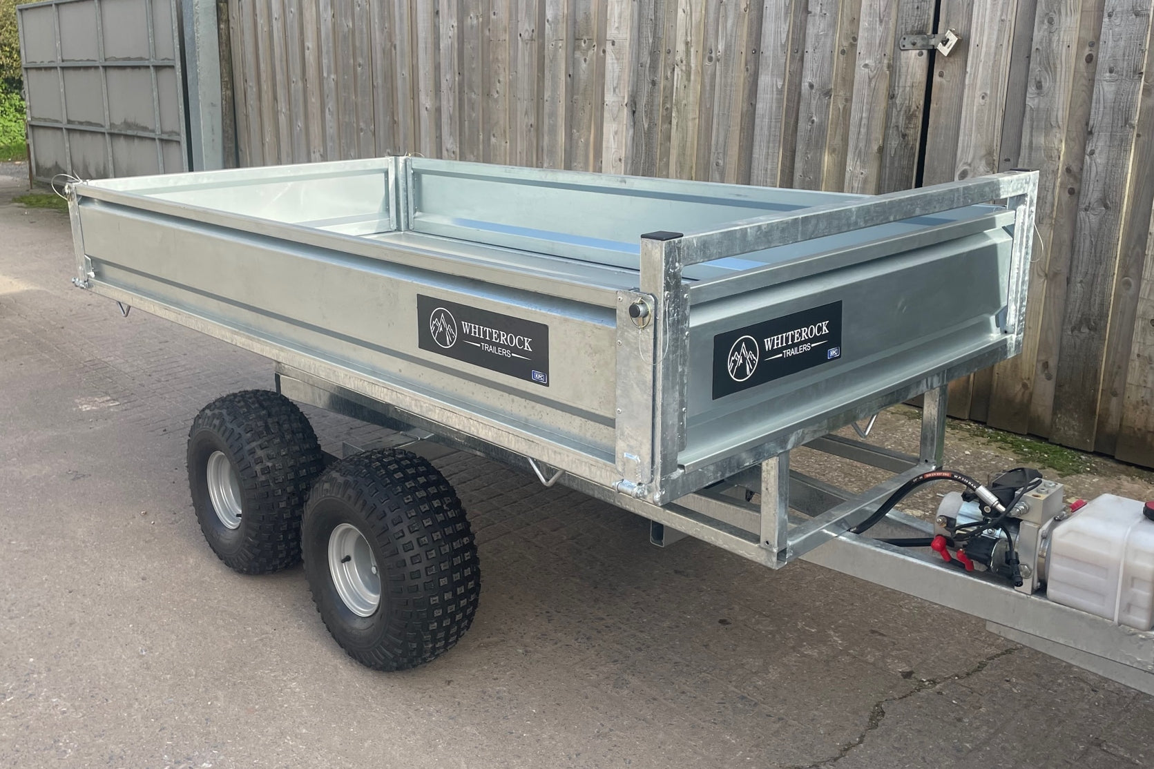 Front view of a flatbed tipping trailer with tipping mechanism mounted.